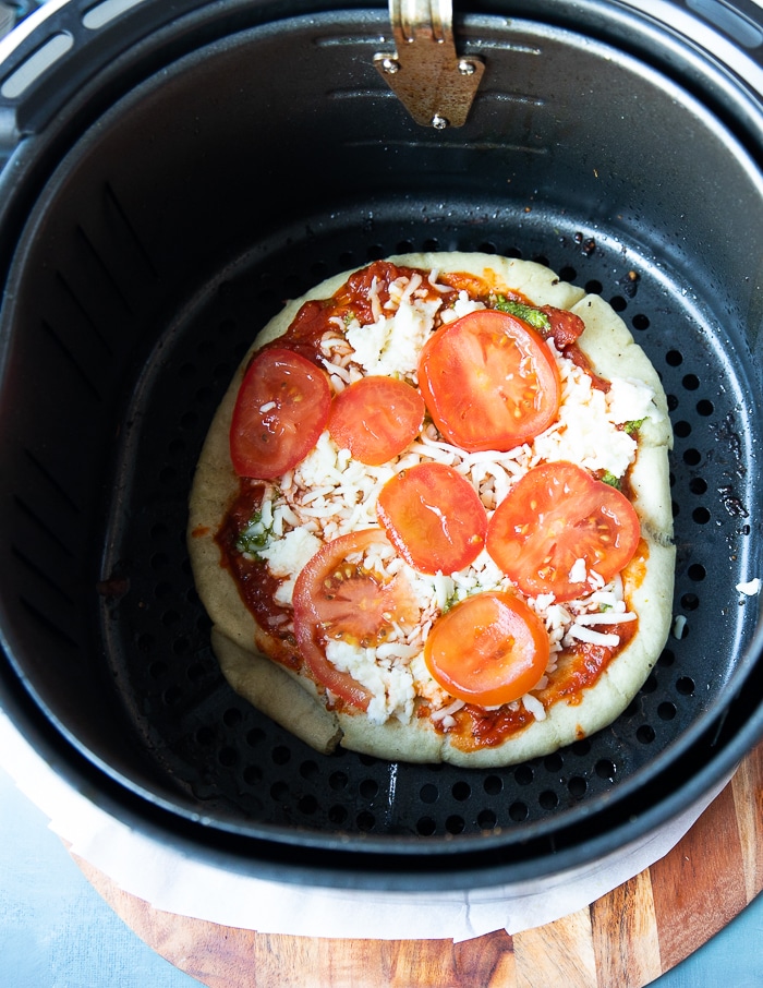 toppings added onto the pizza dough in the air fryer basket to continue air frying