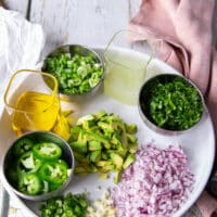 Remaining ingredients to make the tuna ceviche including olive oil, some diced red onions, some diced jalapenos, some cilantro minced, a bowl of lime juice, some avocados diced,