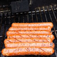 Grilled hot dogs are ready, golden and blistered on the grill and ready to serve