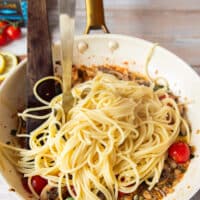 Cooked spaghetti is added to the sauce skillet