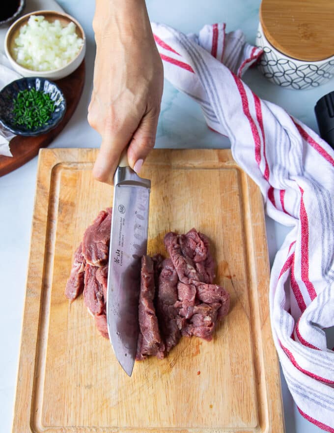 A hand slicing the beef on a cutting board