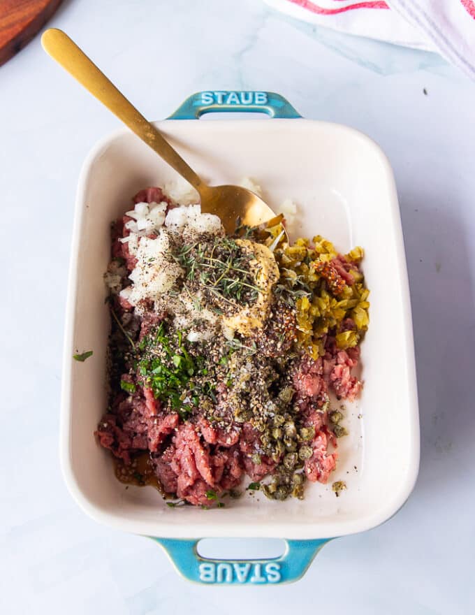 The steak tartare ingredients all added into the beef mixture including onions, capers, mustard, Worcestershire sauce, herbs, salt and pepper