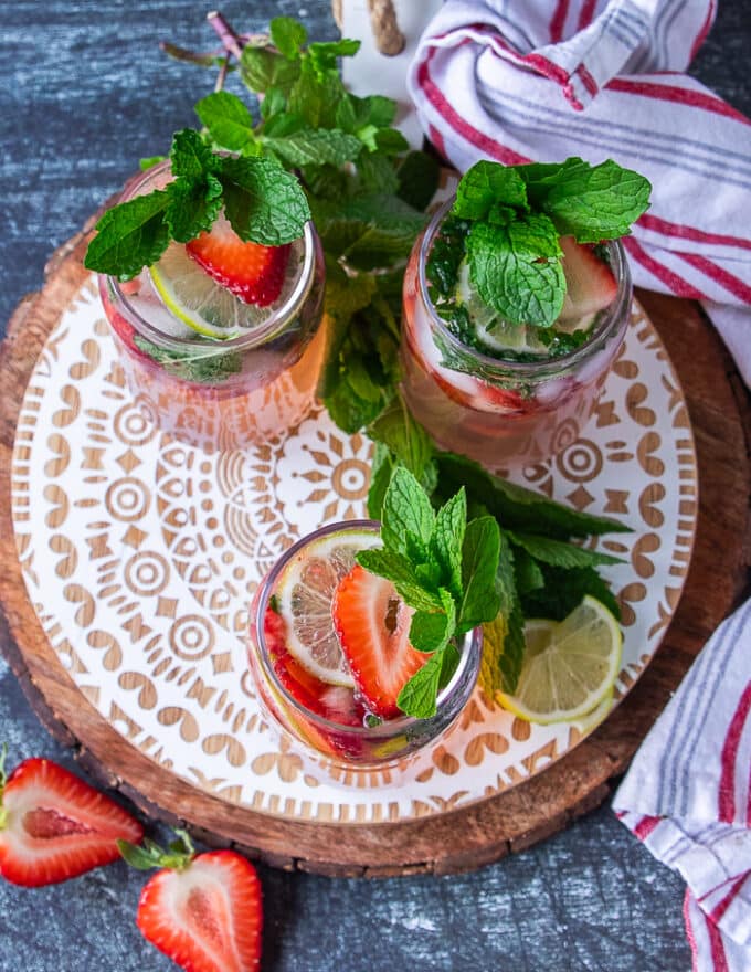 Top view of three strawberry mojito cups ready and garnished showing the bright berries, the fresh mint and lime and the fizzy 