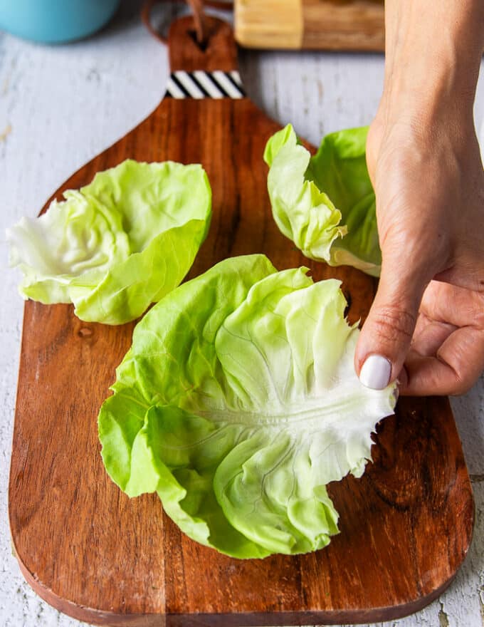 A hand holding a leaf of boston lettuce to show how to make tuna lettuce wraps